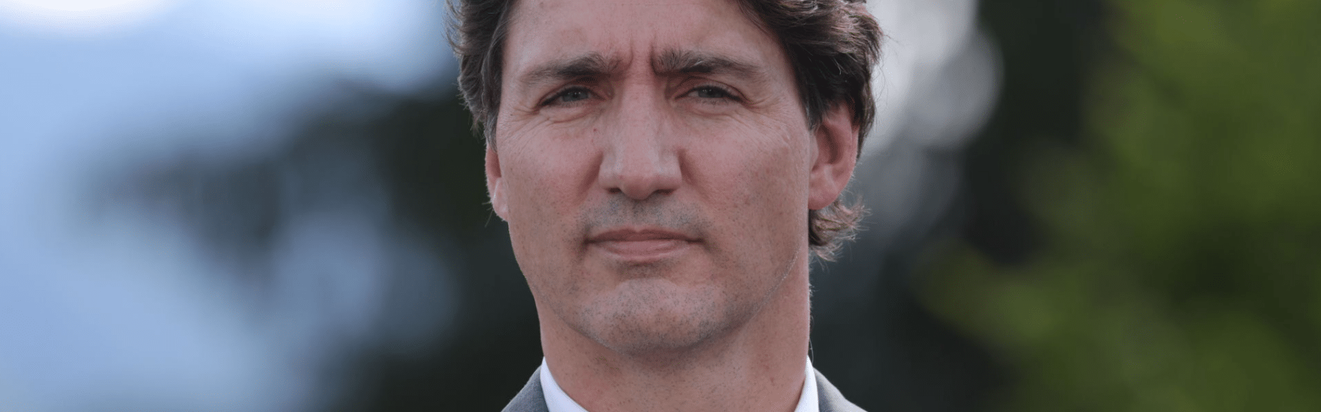 La imagen del ex primer ministro Justin Trudeau sobre un fondo borroso de árboles verdes.